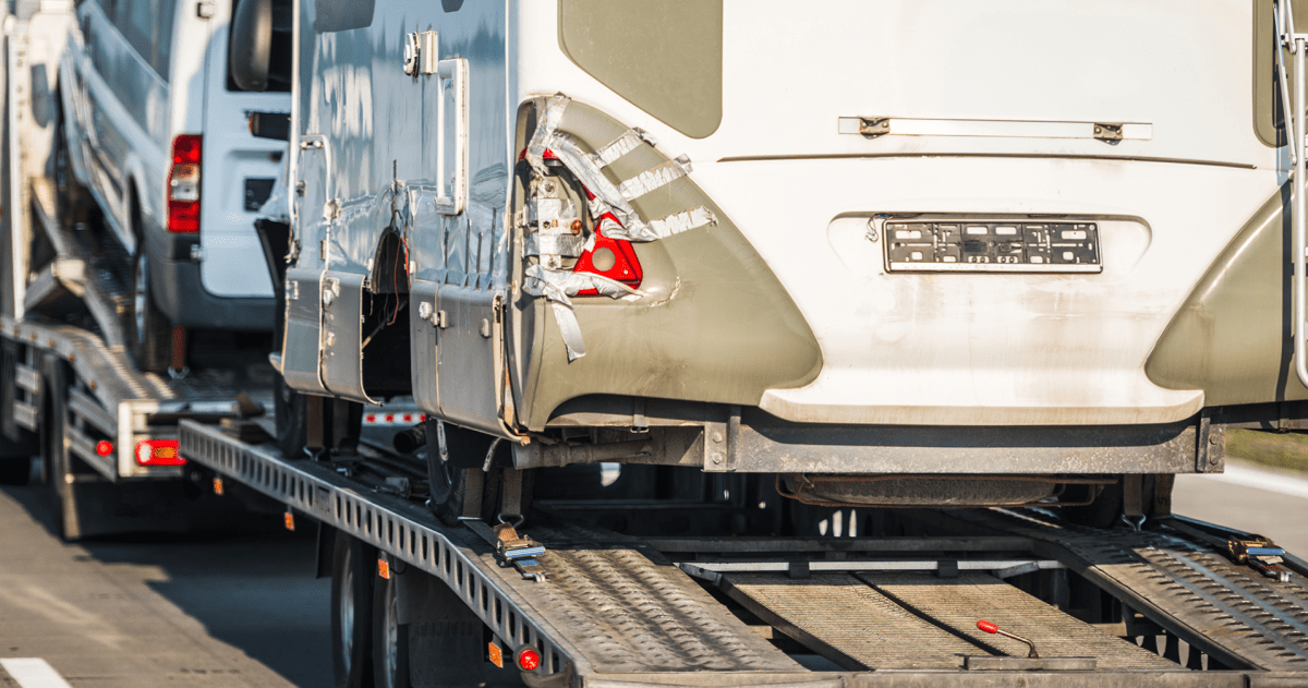Camper met schade wordt vervoerd op een vrachtwagen naar een schadeherstelbedrijf
