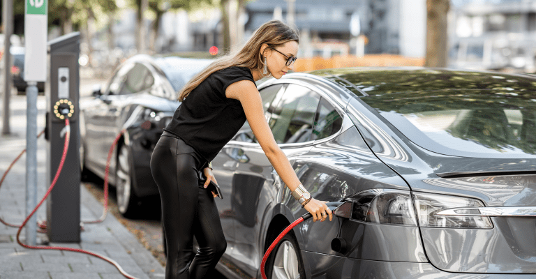 Vrouw sluit oplader aan op elektrische auto